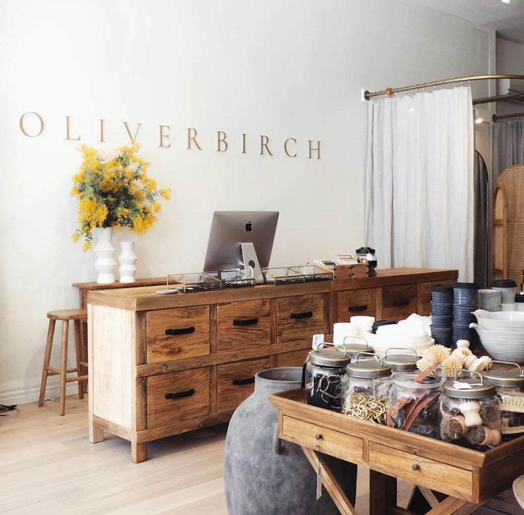 Wooden furniture set with decorative items in a room, featuring the brand 'Oliver Birch'.