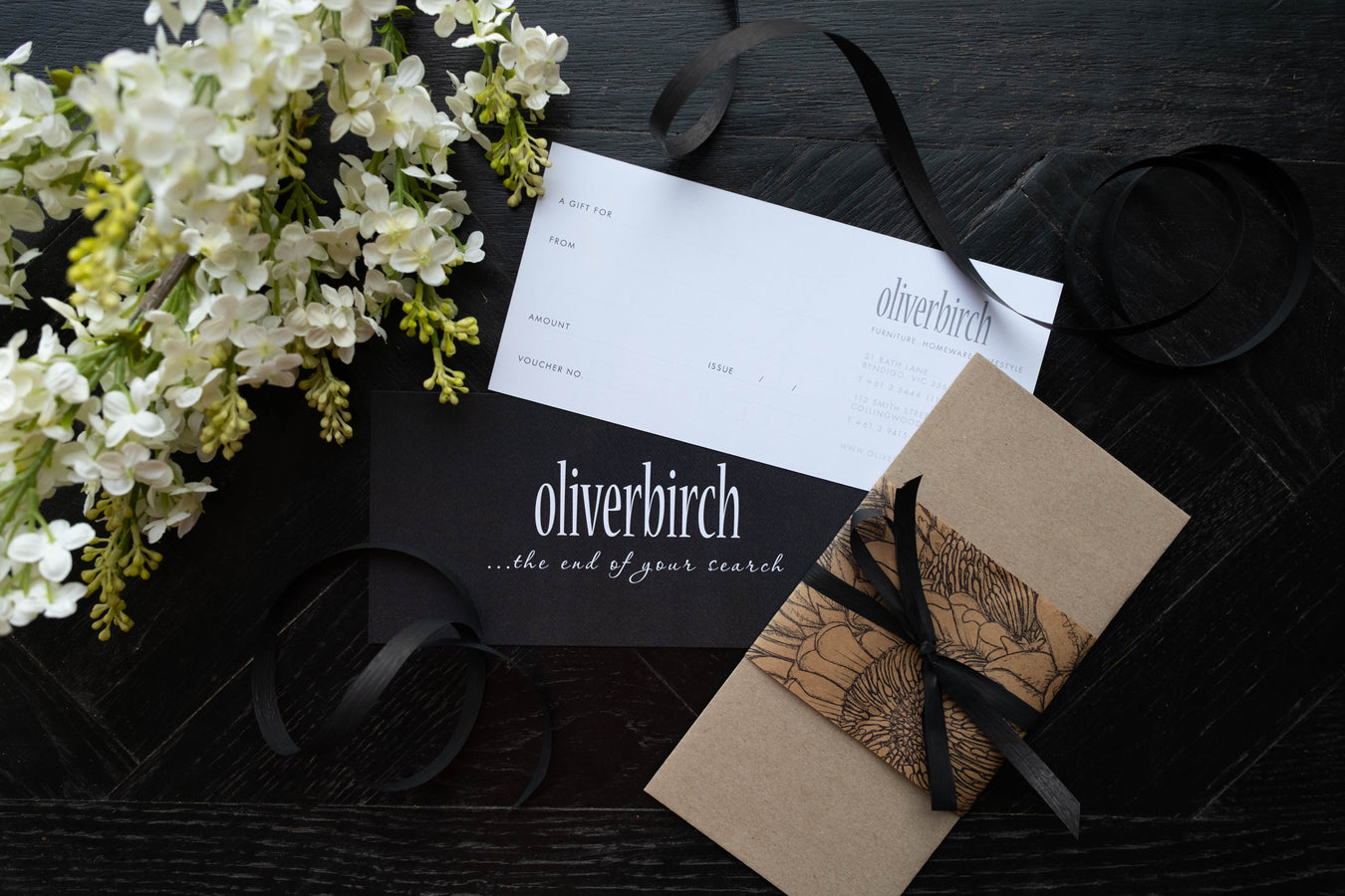 Oliverbirch product packaging with flowers and ribbon on a dark surface
