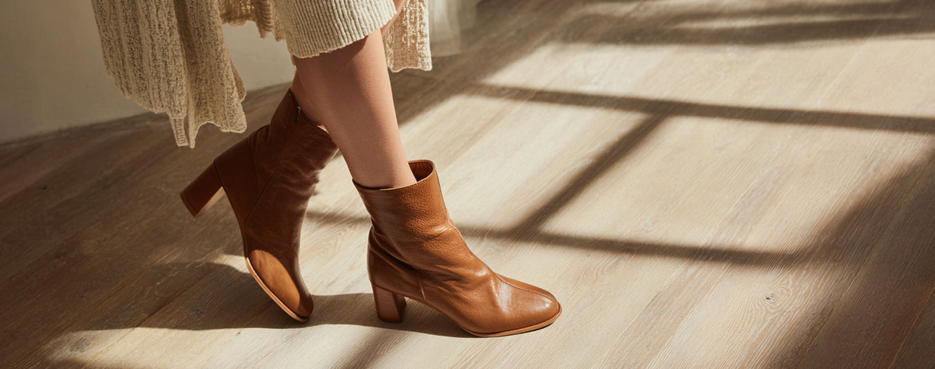 Brown ankle boots on a wooden floor with sunlight casting shadows